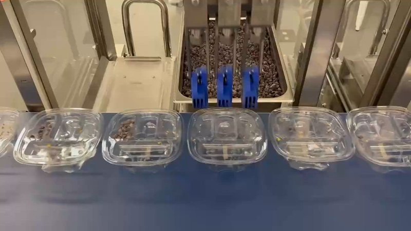 Chef Robotics assembly robot depositing food into a row of meal trays on a conveyor